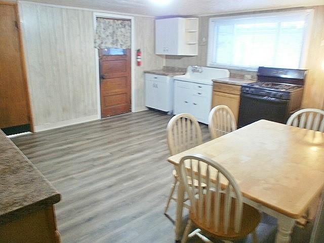 kitchen with light hardwood / wood-style floors, white cabinetry, and black range