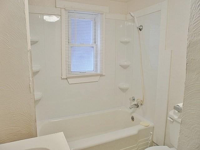 bathroom with bathing tub / shower combination and toilet