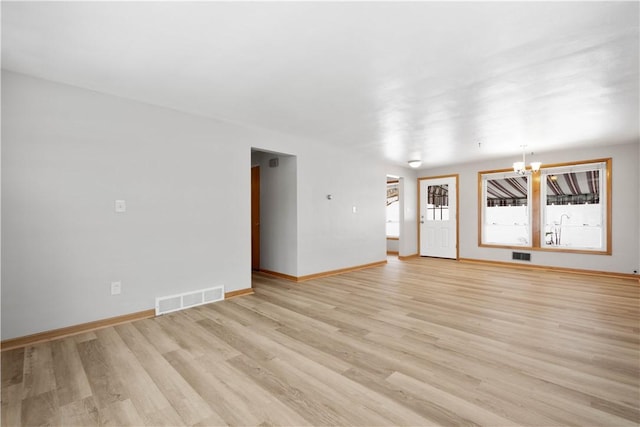 unfurnished living room with light hardwood / wood-style floors and a notable chandelier