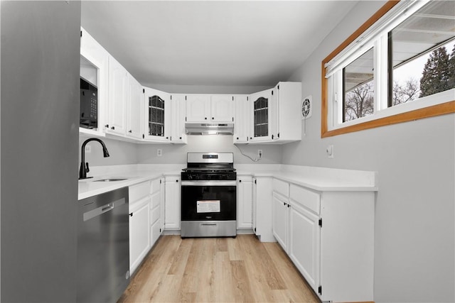 kitchen with white cabinetry, sink, stainless steel appliances, and light hardwood / wood-style flooring