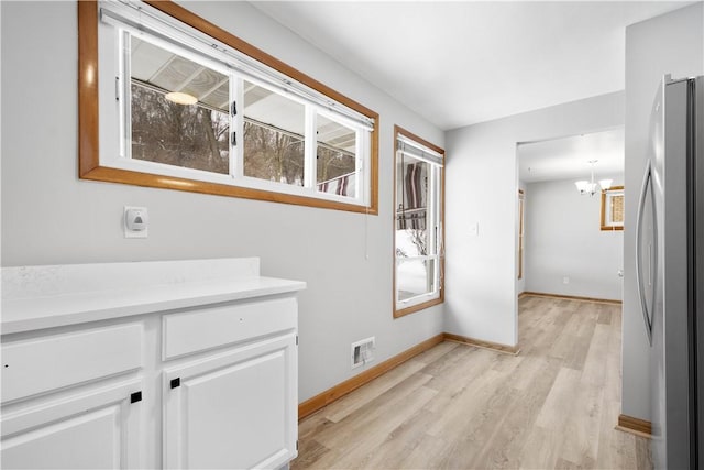 hall with a chandelier and light wood-type flooring