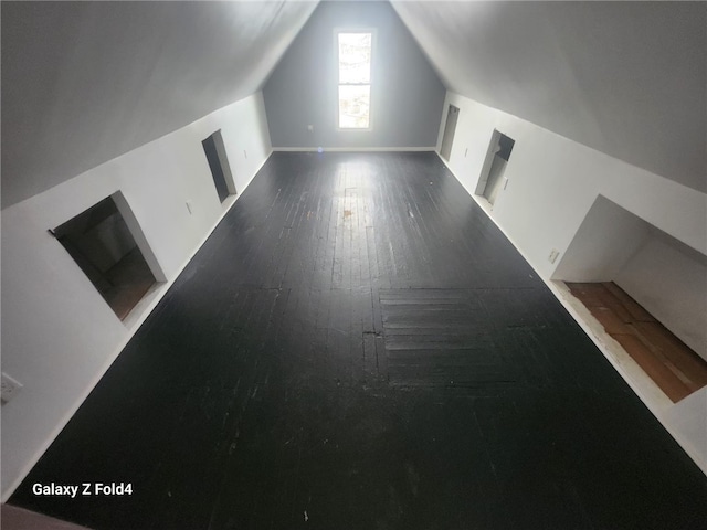 bonus room with dark wood-type flooring and lofted ceiling