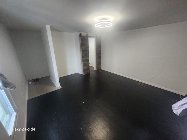 basement featuring a barn door and dark hardwood / wood-style floors