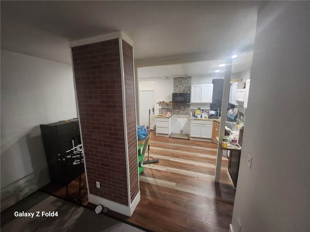 kitchen with backsplash, white cabinetry, and wood-type flooring