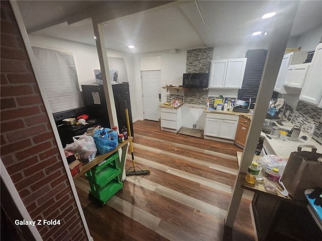 kitchen with tasteful backsplash, white cabinetry, and light wood-type flooring