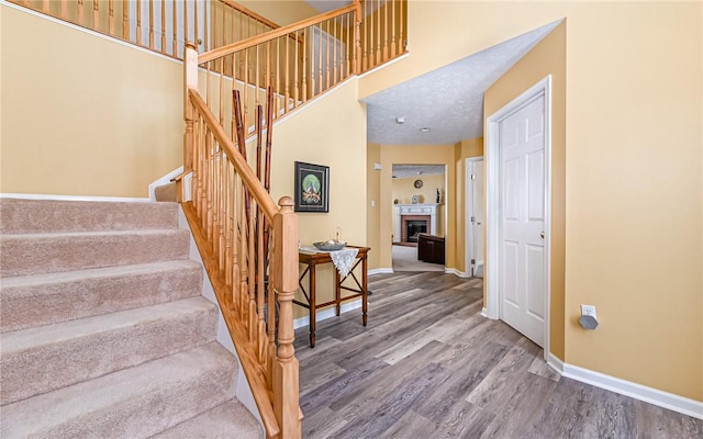 stairs featuring hardwood / wood-style floors and a brick fireplace