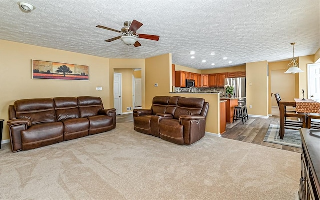 carpeted living room with ceiling fan and a textured ceiling