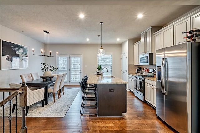 kitchen featuring pendant lighting, a breakfast bar, stainless steel appliances, and an island with sink