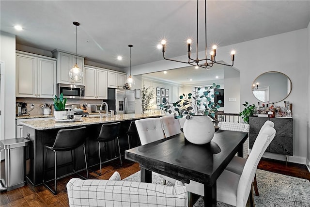 dining area with sink, dark hardwood / wood-style flooring, and a notable chandelier