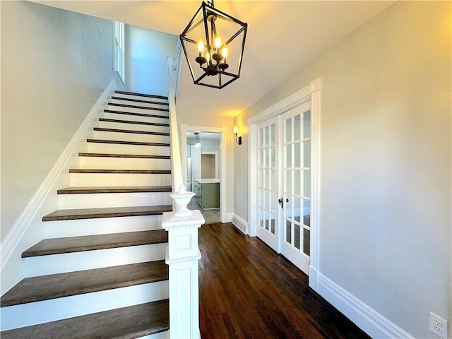 staircase with french doors, a chandelier, and hardwood / wood-style flooring