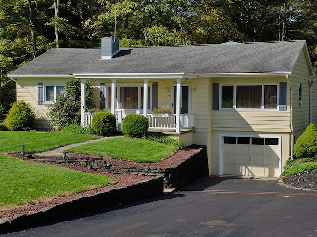 single story home featuring covered porch, a garage, and a front yard