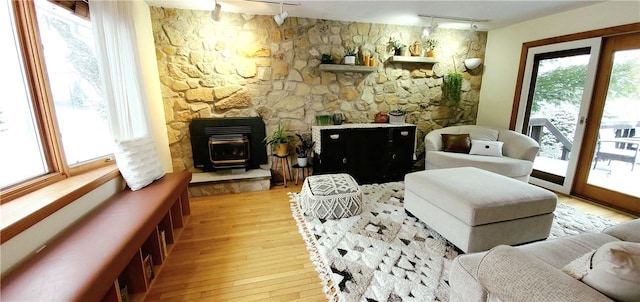 living area with track lighting, a wood stove, a wealth of natural light, and light hardwood / wood-style floors