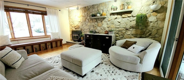 living area featuring rail lighting, light hardwood / wood-style floors, and a wood stove