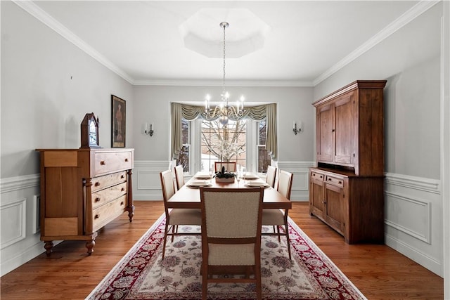 dining space featuring hardwood / wood-style flooring, an inviting chandelier, and ornamental molding