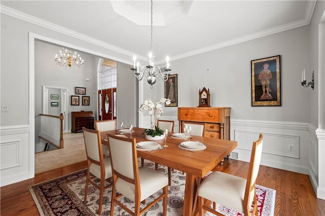 dining space featuring hardwood / wood-style flooring, crown molding, and a notable chandelier