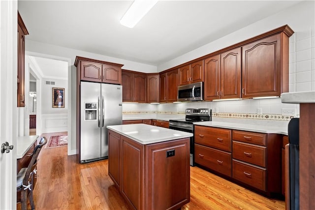 kitchen with decorative backsplash, a kitchen island, light hardwood / wood-style floors, and appliances with stainless steel finishes