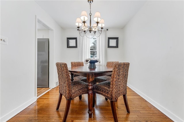 dining room featuring wood-type flooring and an inviting chandelier