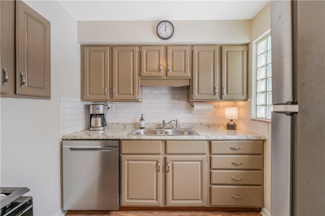 kitchen featuring sink, light stone counters, stainless steel dishwasher, backsplash, and stove