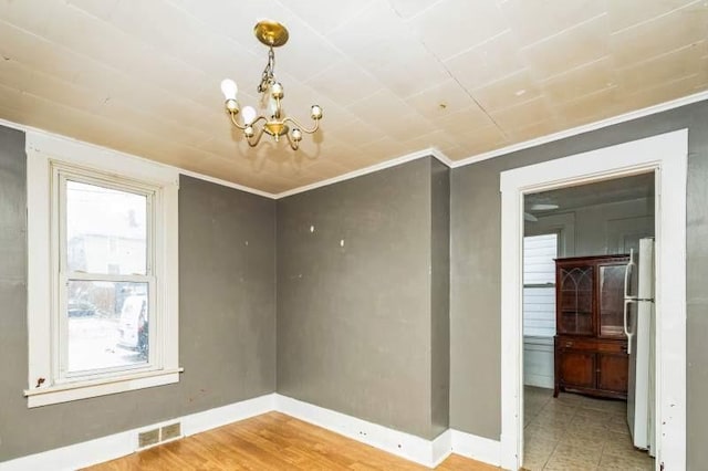 spare room with ornamental molding and a chandelier