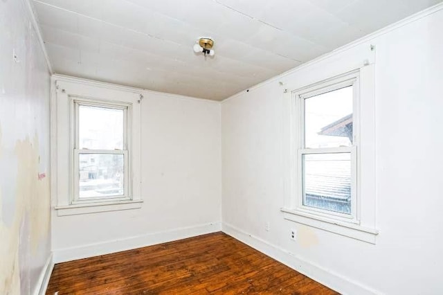 spare room featuring ornamental molding and dark wood-type flooring