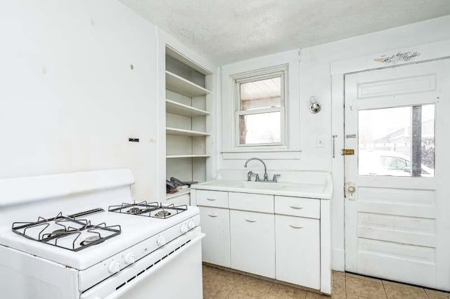 kitchen featuring white cabinetry, a textured ceiling, light tile patterned floors, and gas range gas stove