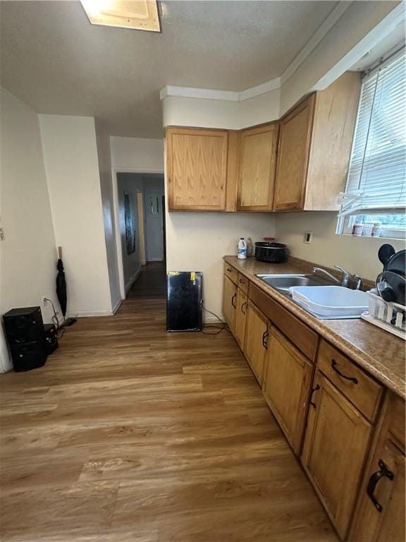 kitchen with crown molding, sink, and wood-type flooring