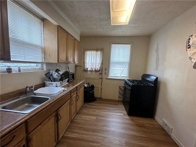 kitchen featuring hardwood / wood-style flooring, black stove, sink, and a textured ceiling