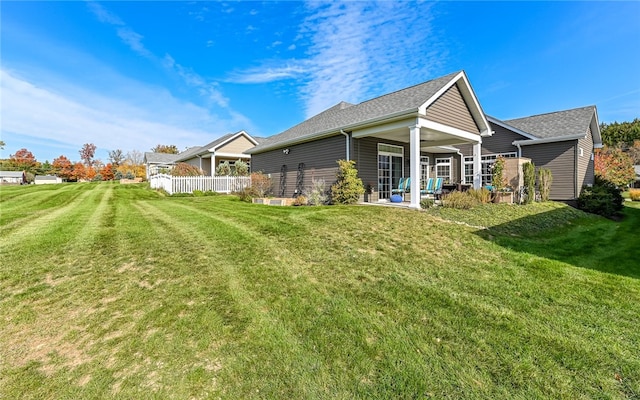 rear view of property featuring a lawn and a patio area