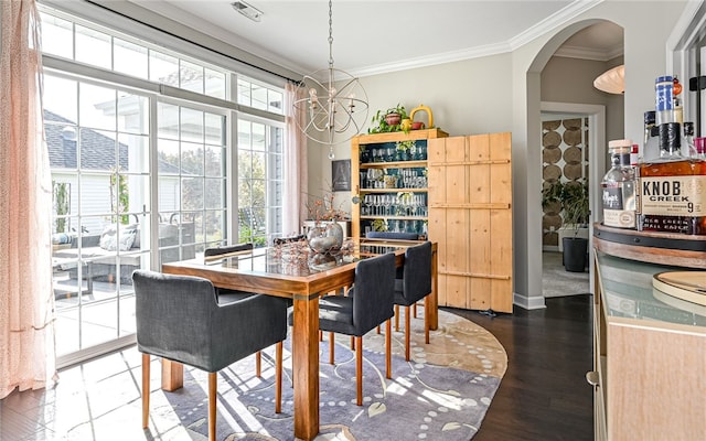 dining area featuring dark hardwood / wood-style floors, crown molding, and an inviting chandelier