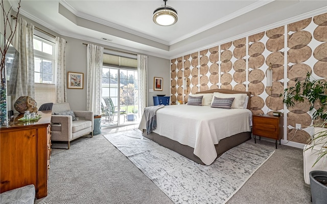 carpeted bedroom with access to outside, a tray ceiling, and ornamental molding