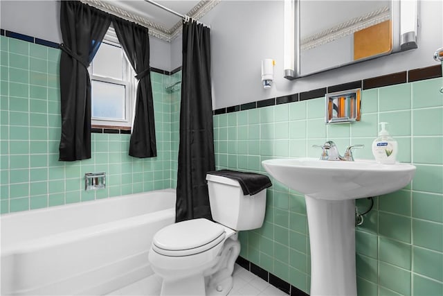 bathroom with tile patterned floors, shower / bathtub combination with curtain, toilet, and tile walls