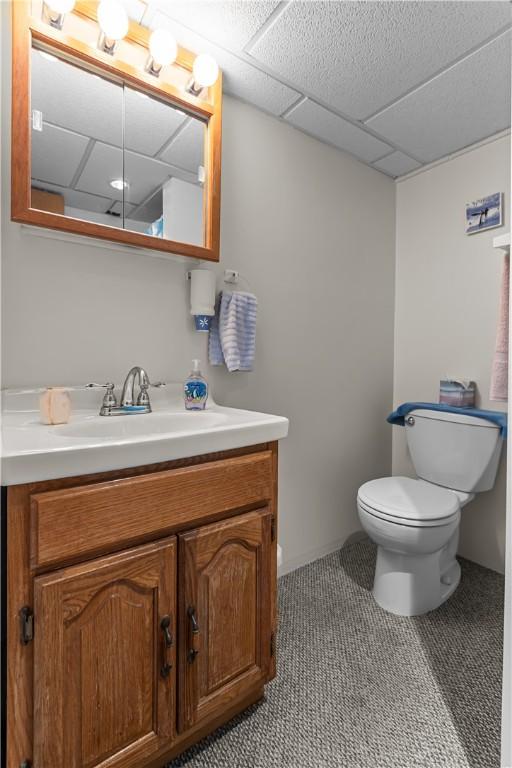 bathroom featuring vanity, toilet, and a drop ceiling