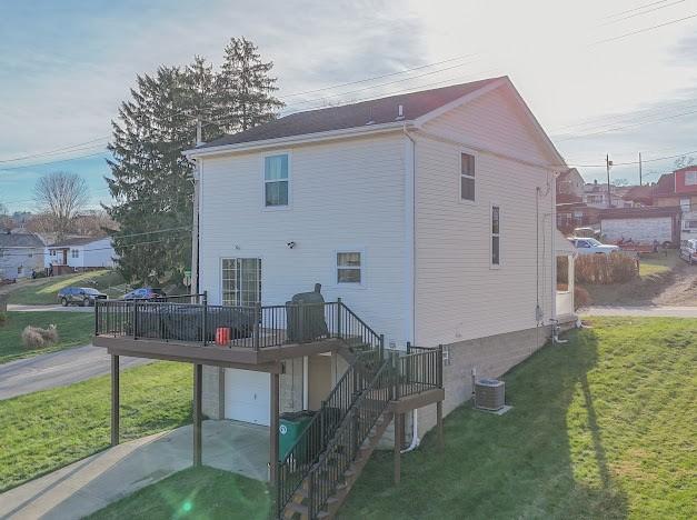 back of house with a lawn, a garage, a deck, and central AC