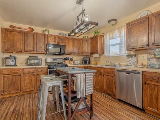 kitchen with pendant lighting, hardwood / wood-style floors, stainless steel appliances, and sink