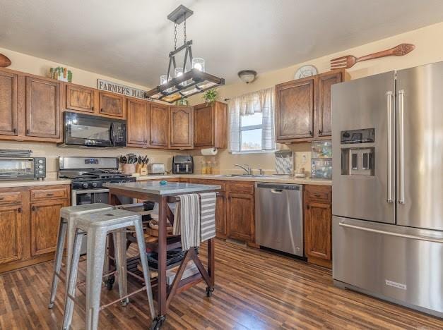 kitchen featuring decorative light fixtures, dark hardwood / wood-style flooring, stainless steel appliances, and sink