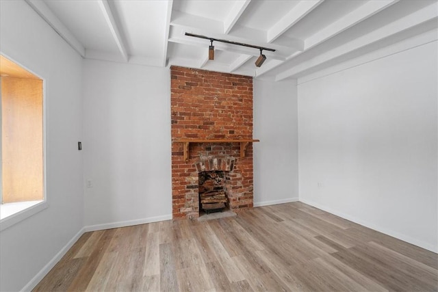 unfurnished living room with beamed ceiling, light wood-type flooring, and a fireplace