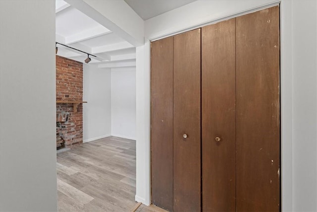 corridor featuring beam ceiling and light hardwood / wood-style flooring