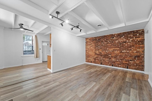 unfurnished room with ceiling fan, brick wall, track lighting, and hardwood / wood-style flooring