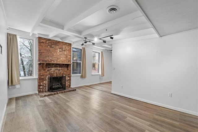 unfurnished living room featuring a fireplace, wood-type flooring, and beam ceiling