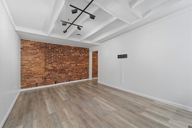 spare room with beamed ceiling, light hardwood / wood-style flooring, and brick wall