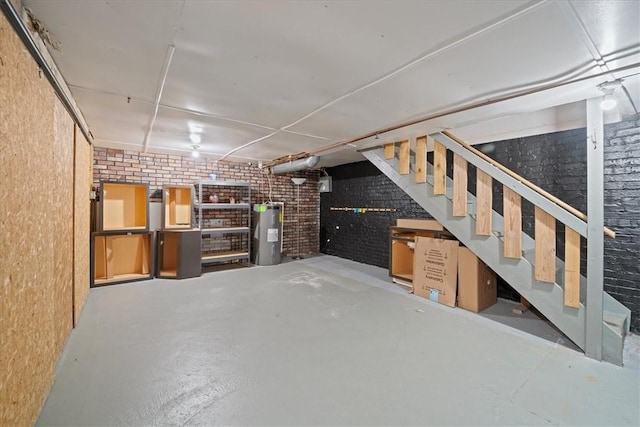 basement featuring water heater and brick wall