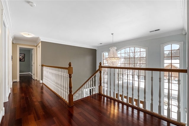 corridor with dark hardwood / wood-style flooring, ornamental molding, and a chandelier