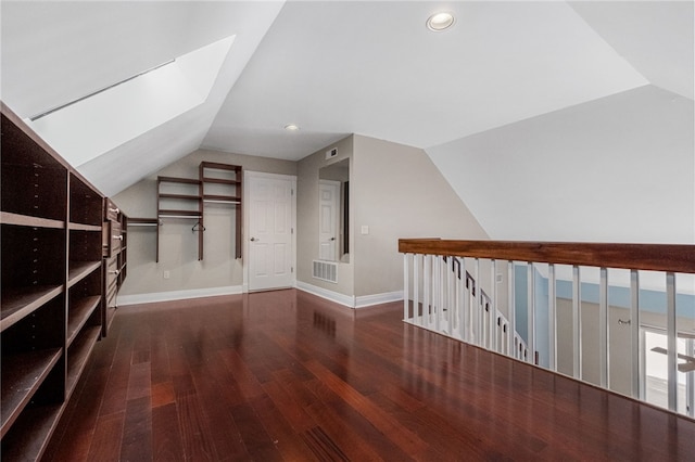 additional living space featuring lofted ceiling with skylight and dark wood-type flooring