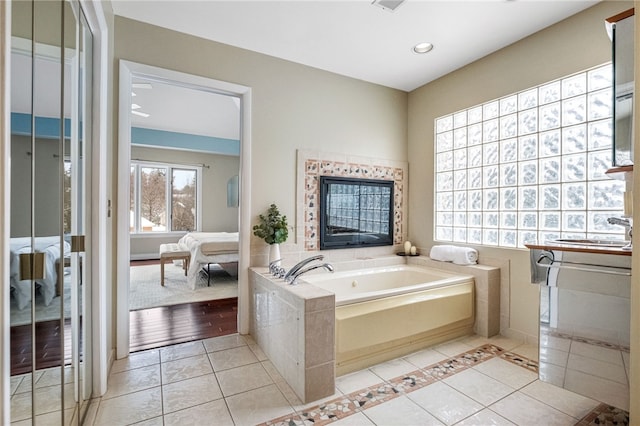 bathroom with tile patterned flooring, a relaxing tiled tub, and sink