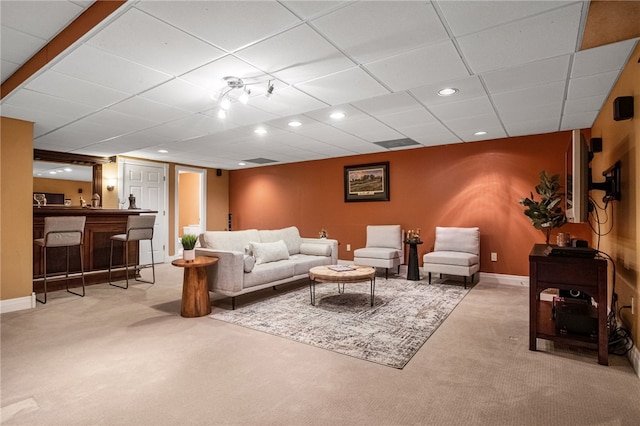 carpeted living room with a drop ceiling and bar area