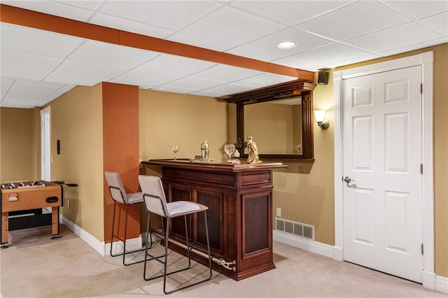 bar with light carpet and a paneled ceiling