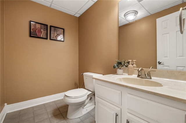 bathroom featuring tile patterned flooring, a drop ceiling, toilet, and vanity