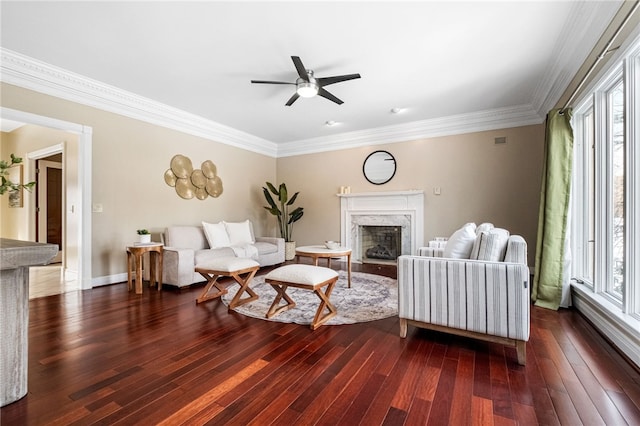 living room featuring dark hardwood / wood-style floors, ceiling fan, a premium fireplace, and ornamental molding