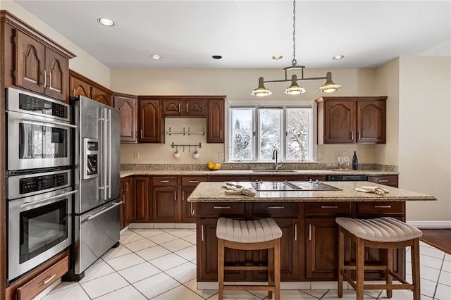 kitchen with a breakfast bar, dark brown cabinetry, stainless steel appliances, sink, and a kitchen island