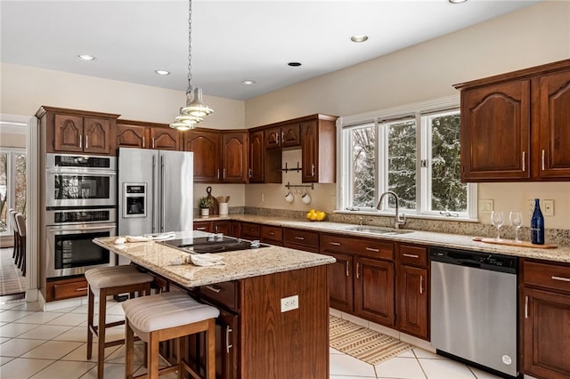 kitchen with a center island, sink, appliances with stainless steel finishes, light tile patterned flooring, and a breakfast bar area